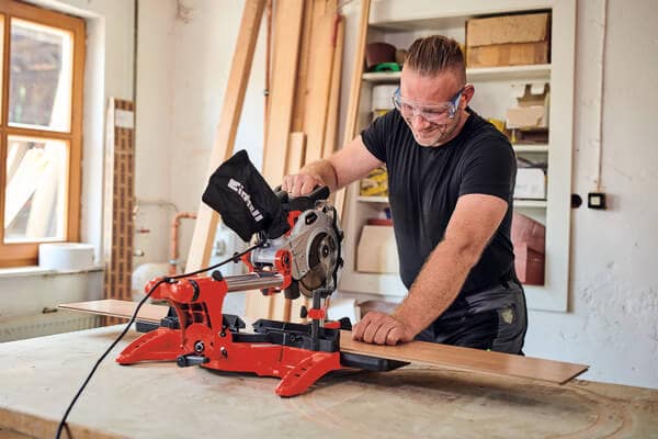 Scie à onglet radiale Einhell TC-SM 2131/1 Dual Test | Avis 2 Homme qui se sert d'une scie à onglet radiale Einhell TC-SM 2131/1 Dual pour couper une planche de bois